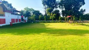 a large green field with a swing set in the middle at Nandini Homestay in Dehradun