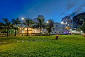 a large white building with palm trees in front of it at Palette - Hotel Bon Sejour in Puducherry