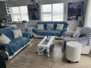uma sala de estar com sofás azuis e uma mesa em SONVANGER VILLA YZERFONTEIN em Yzerfontein