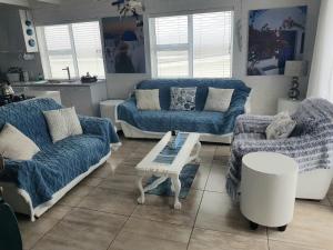 a living room with blue couches and a table at SONVANGER VILLA YZERFONTEIN in Yzerfontein