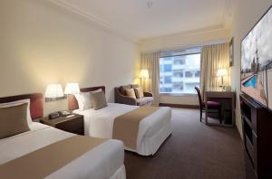 香港にあるプルデンシャル ホテルのベッド2台とテレビが備わるホテルルームです。