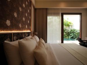 a bedroom with a bed with white pillows and a window at Daun Lebar Villas in Payangan +118 photos