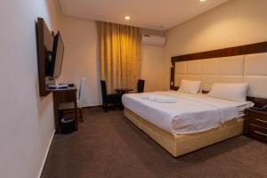 ein Hotelzimmer mit einem großen Bett und einem Schreibtisch in der Unterkunft Dar Hotel Suites in Dschidda