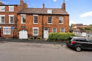 ein schwarzes Auto, das vor einem Backsteinhaus parkt in der Unterkunft Archway House in Grantham