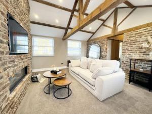 a living room with a white couch and a brick wall at Whitkirk Cottage in Leeds