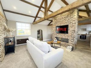 a living room with a white couch and a fireplace at Whitkirk Cottage in Leeds