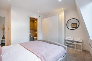 a white bedroom with a bed and a mirror at Farringdon/St Pancras penthouse in London