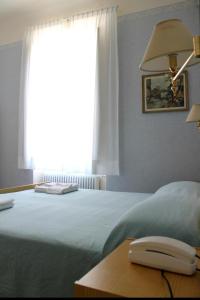 Un dormitorio con una cama y un teléfono en una mesa. en Hotel VILLA PINA, en Senigallia
