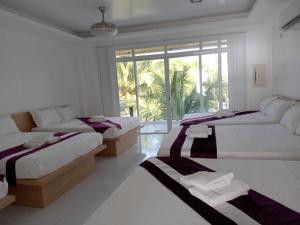 a white room with two beds and a window at Seaview Emerald Adoces Beach Resort in Morong