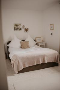 ein weißes Schlafzimmer mit einem großen Bett mit Kissen in der Unterkunft Ferienwohnung Häserhof in Raddestorf