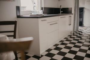 une cuisine avec des placards blancs et un sol en damier noir et blanc dans l'établissement Ferienwohnung Häserhof, à Raddestorf