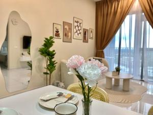 a dining room with a table and flowers on it at Cozy 1-4Pax SkyTrees AeonBukitIndah NetflixWifi in Johor Bahru