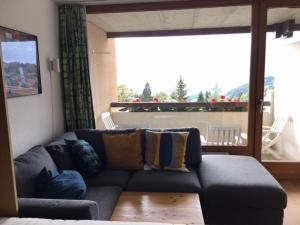 uma sala de estar com um sofá e uma grande janela em Residence Panorama em Villars-sur-Ollon