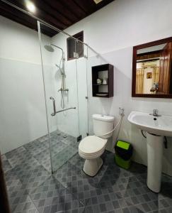 uma casa de banho com um chuveiro, um WC e um lavatório. em Singrarat Hotel em Luang Prabang