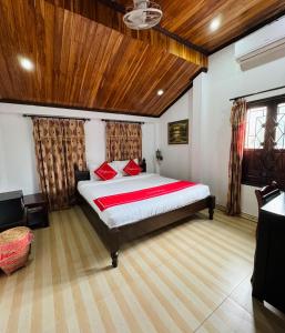 a bedroom with a large bed and a wooden ceiling at Singrarat Hotel in Luang Prabang