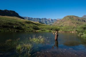 a man standing in the water in a river at Cathedral Peak Hotel in Amanzana
