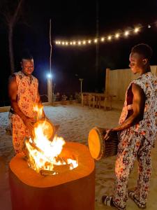 zwei Männer stehen um eine Feuerstelle am Strand in der Unterkunft CAJOU LODGE in Bubaque