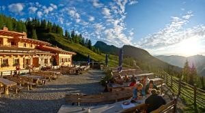 a group of people sitting on benches in front of a building at Berggasthof Loosbühelalm in Grossarl