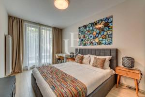 a bedroom with a large bed with a painting on the wall at Oslo: A modern furnished apartment with parking in Sofia