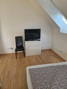 Un dormitorio con una cama, un televisor y una silla. en Apartment am Stadtrand zu Graz, en Graz