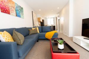 a living room with a blue couch and a tv at Peaceful Central City 2 bed pad w/carpark in Christchurch