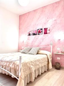 ein Schlafzimmer mit einem weißen Bett und einer rosa Wand in der Unterkunft Minù house in Scalea