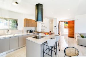 een keuken met witte kasten en een bar met krukken bij Akamas Bay Villa 42 by BeCyprus in Neo Chorio