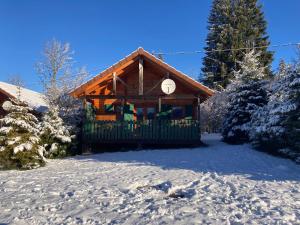 Lac des Rouges TruitesCamping-Chalets La Favière的雪地里的小木屋，树木被雪覆盖