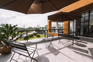 eine Terrasse mit 2 Stühlen, einem Tisch und einem Sonnenschirm in der Unterkunft Beforesunset in Ban Chang Kham Luang