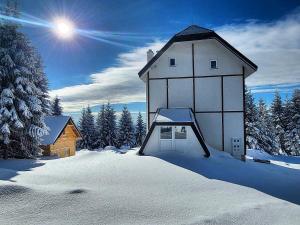 a building in the snow next to a house at Vila Kruna Sunčani Breg in Kopaonik