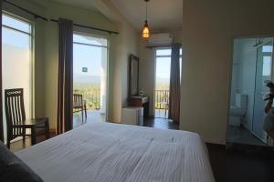 a bedroom with a white bed and a balcony at Villa Arunalu Kandy in Kandy