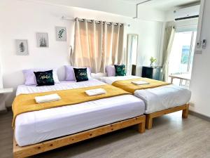 two large beds in a room with white walls at 54place​สะพานใหม่ดอนเมือง in Ban Don Muang