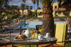 Una mesa con un plato de comida y vasos de jugo de naranja. en Pachi Beach Atlantic Garden Corralejo, en Corralejo