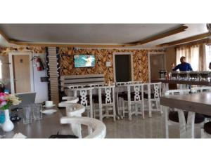 Serene Guest House, Pasighat, Arunachal Pradesh في باسيغات: مطعم بكراسي بيضاء ورجل واقف عند كاونتر