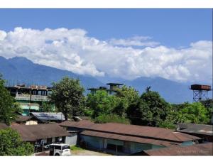 un grupo de edificios y árboles con montañas en el fondo en Serene Guest House, Pasighat, Arunachal Pradesh, en Pāsighāt