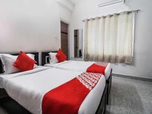 2 camas en una habitación de hotel con almohadas rojas en OYOFlagship Hillside Hotel Kukatpally en Kukatpally