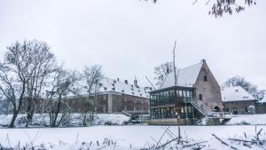 un grand bâtiment en briques avec de la neige au sol dans l'établissement Schloss Wissen, à Weeze