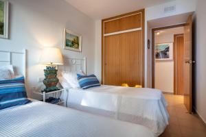 Un dormitorio con dos camas y una lámpara sobre una mesa. en AT135 Els Pins, primera línea, piscina, muy bien equipado, en Torredembarra 32 fotos más