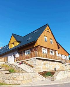 une grande maison en bois avec un toit noir dans l'établissement Penzion Adler, à Police nad Metují