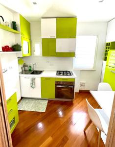 cocina con armarios verdes y blancos y suelo de madera en Via Umbria 25 Luxury Suites en Roma