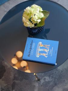 a book sitting on a table with a vase of flowers at Hotel du Nord Alster - auf der Uhlenhorst - SELF CHECK-IN in Hamburg