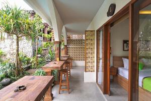 eine Außenterrasse mit Holztischen und Bänken in der Unterkunft Green Bali Guest House in Munggu