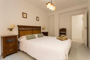 um quarto com uma grande cama branca e uma cabeceira em madeira em Apartamento Mulhacen Centro em Granada