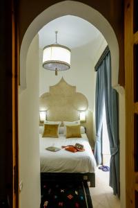 a bedroom with a large bed with a chandelier at Riad Alech in Essaouira