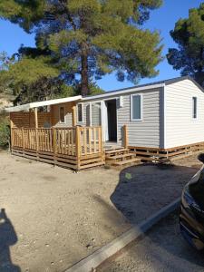 a small white house with a porch and a yard at Charmant mobil-home 97 in Narbonne