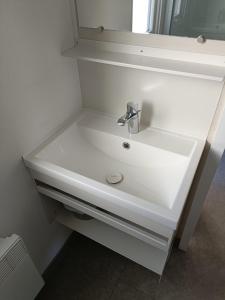 La salle de bains est pourvue d'un lavabo blanc et d'un miroir. dans l'établissement Charmant mobil-home 97, à Narbonne