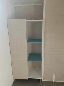 une armoire blanche avec des étagères bleues dans une pièce dans l'établissement Charmant mobil-home 97, à Narbonne