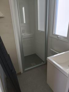 La salle de bains est pourvue d'une douche, d'un lavabo et d'un miroir. dans l'établissement Charmant mobil-home 97, à Narbonne