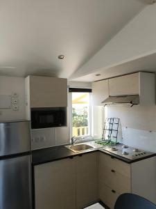 a kitchen with white cabinets and a stainless steel refrigerator at Charmant mobil-home 97 in Narbonne