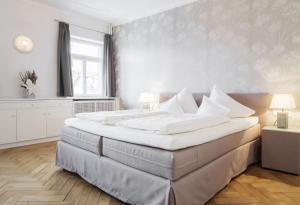 a large bed in a bedroom with white walls at Boutique Hotel Friesinger in Kressbronn am Bodensee